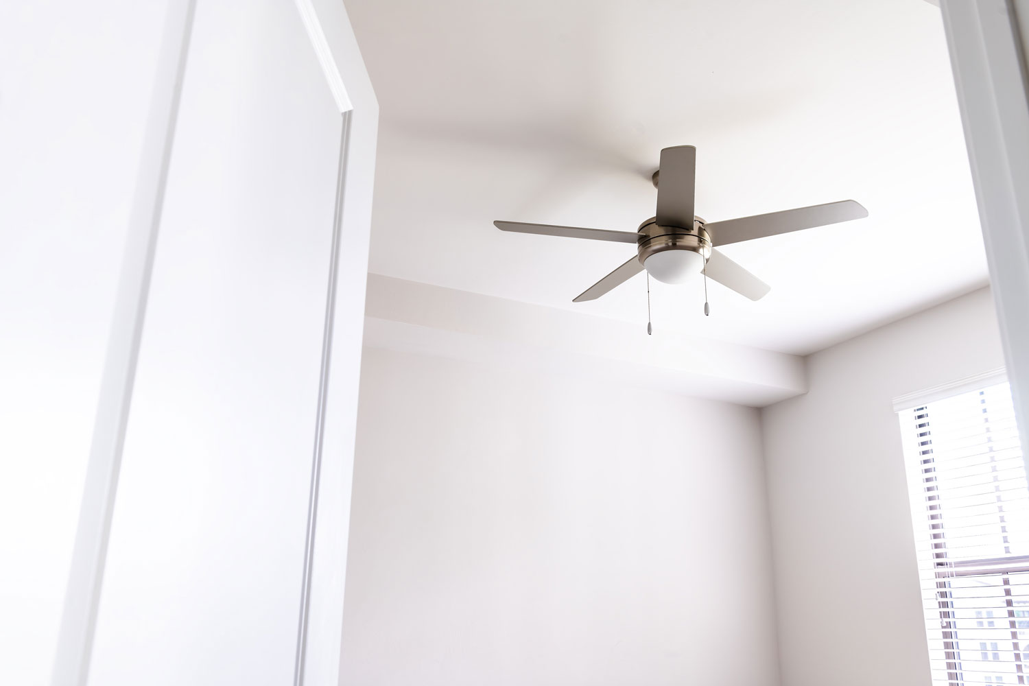 A white ceiling fan installed inside a bedroom