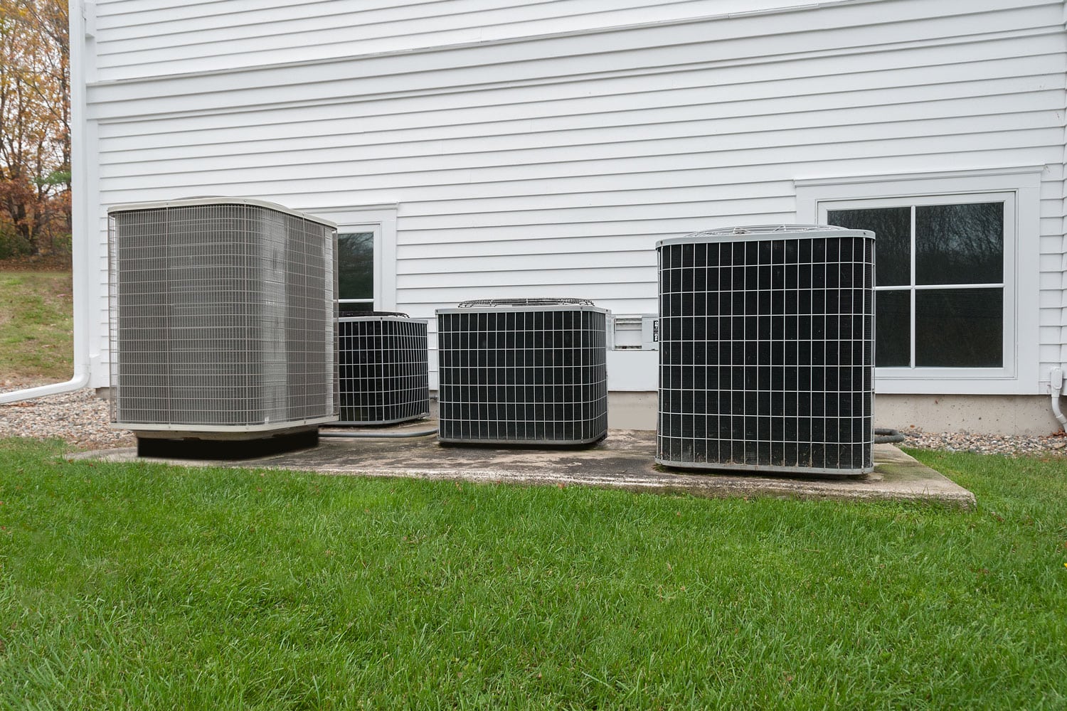 AC units mounted on a concrete slab behind the house