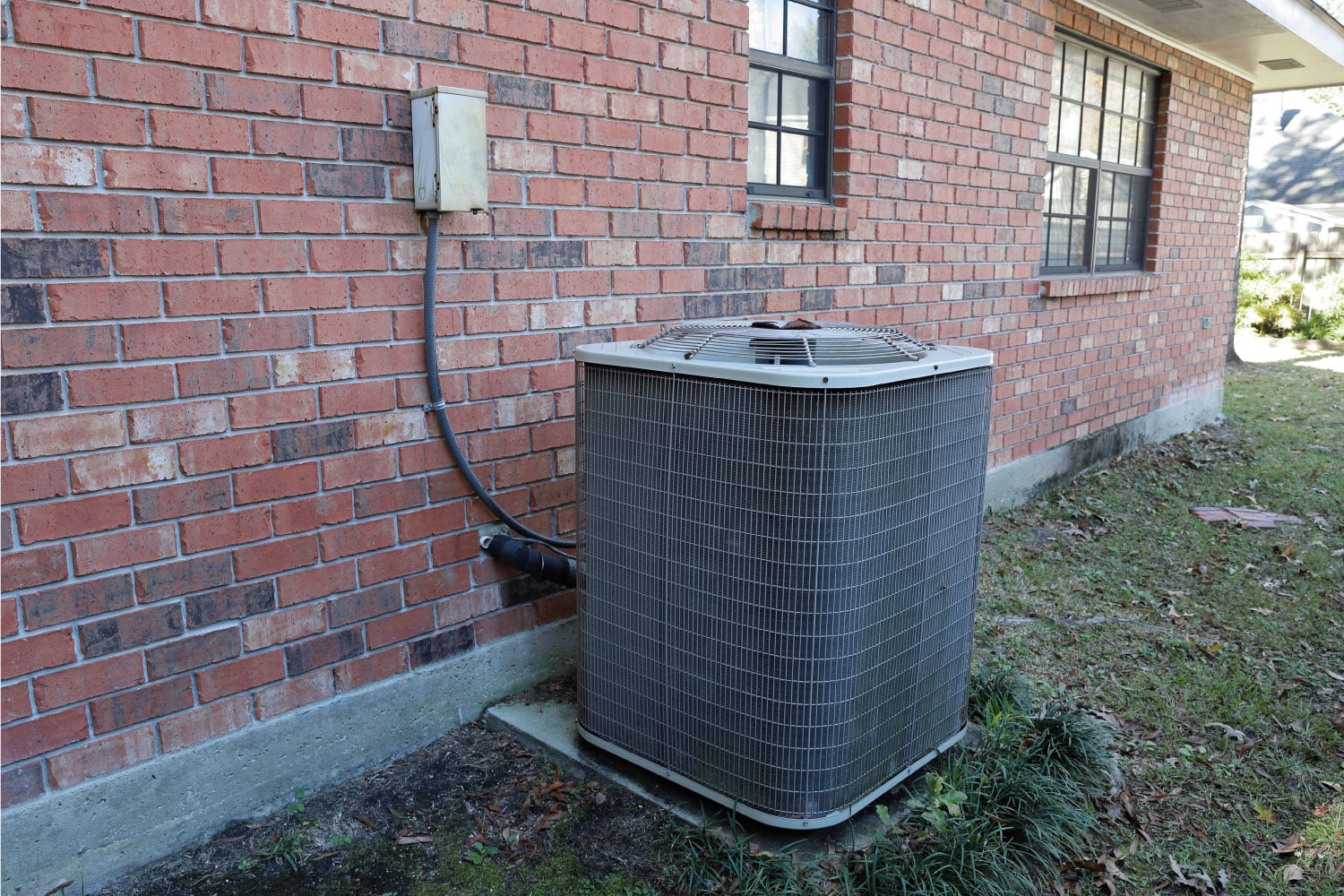 Air Conditioner compressor next to brick house