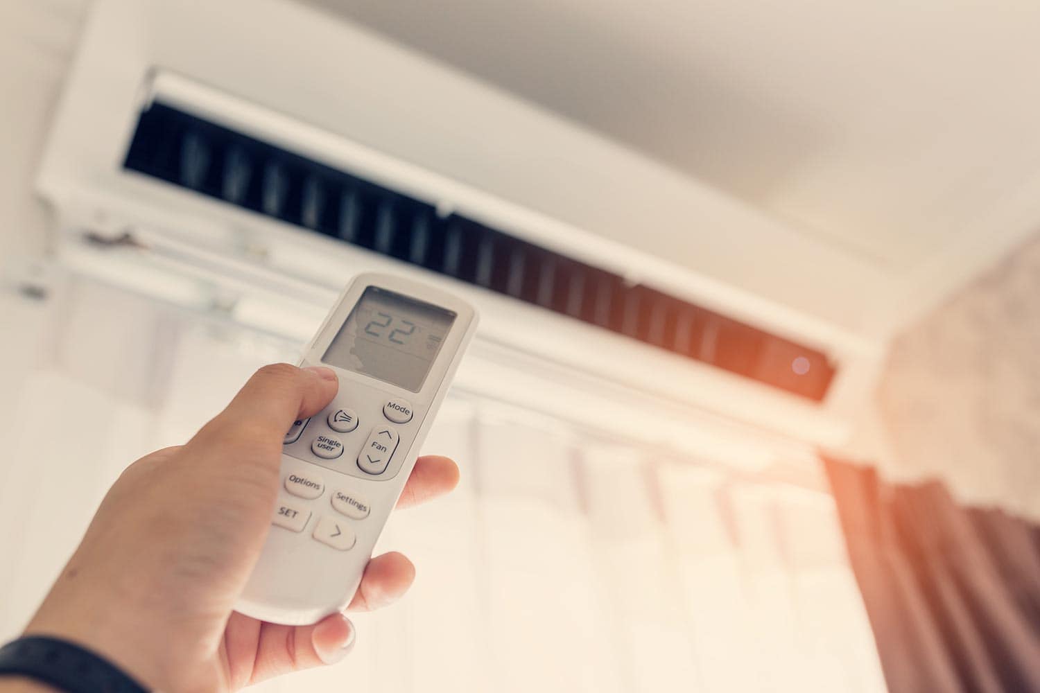 Air conditioner inside the room with woman operating remote controller