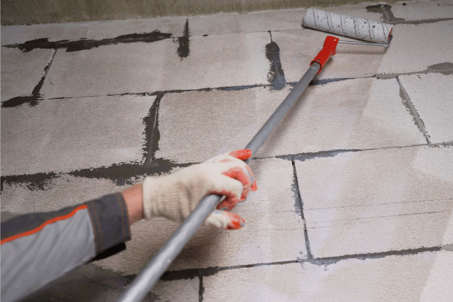 An industrial technician seals the wall of a building with a roller