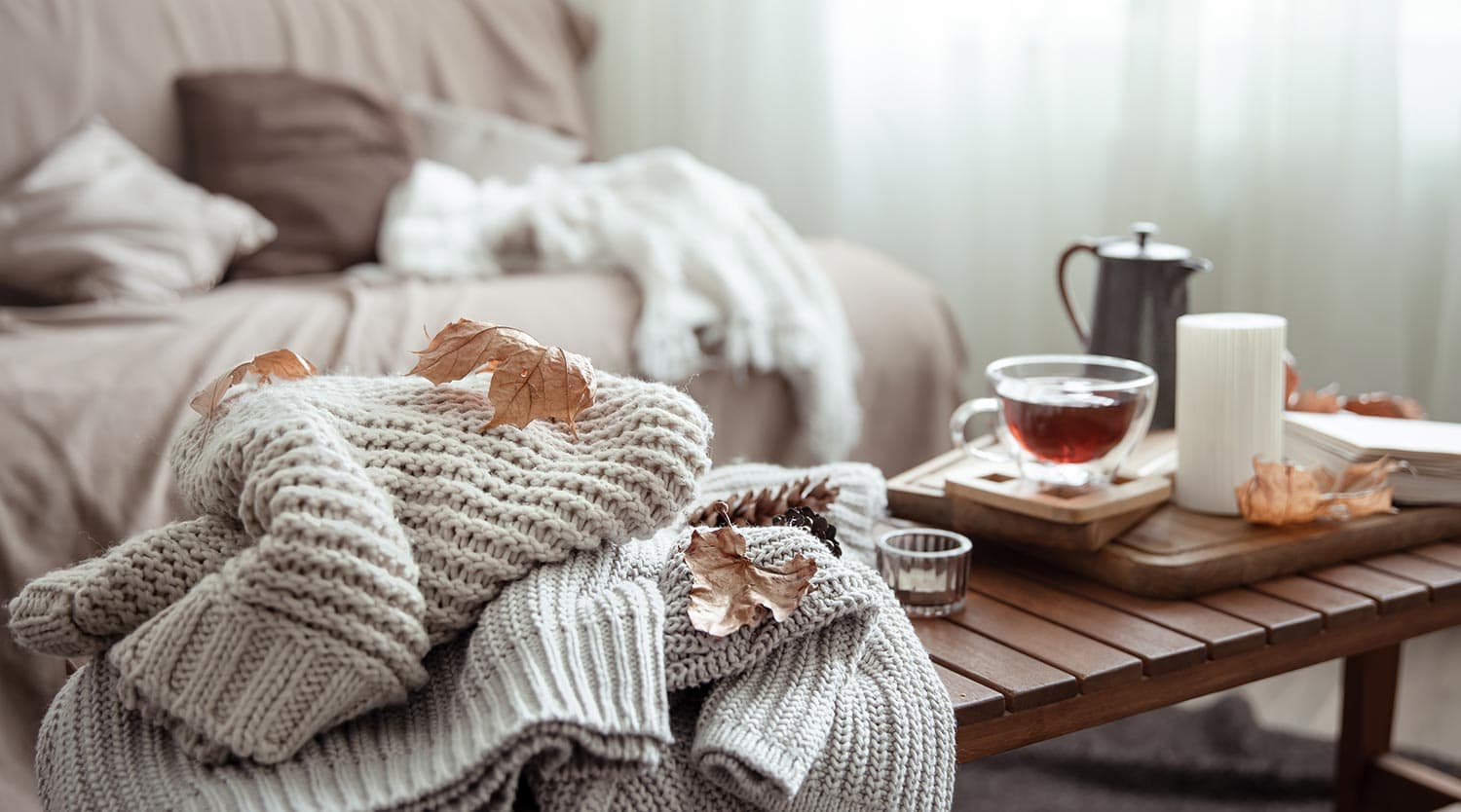 Autumn home composition with tea, candle, book and knitted elements