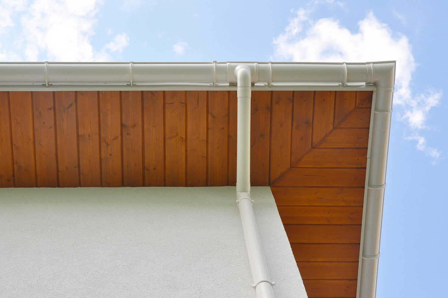 Close up on New Rain Gutter, Downspout, Soffit Board, Fascia Board Installation Against Blue Sky.