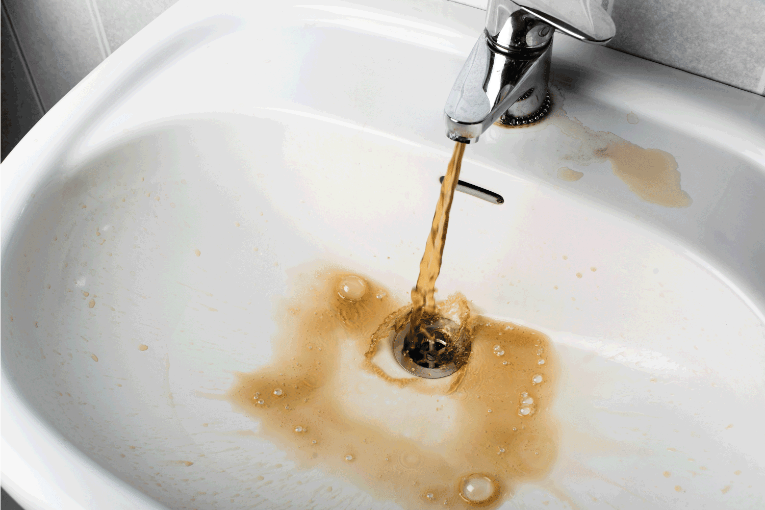 Dirty brown water running into a white sink.