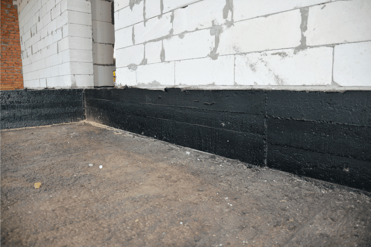 Foundation bitumen waterproofing. Building house construction with waterproofing spray-on tar. Should You Seal Your Basement Wall [And How To]