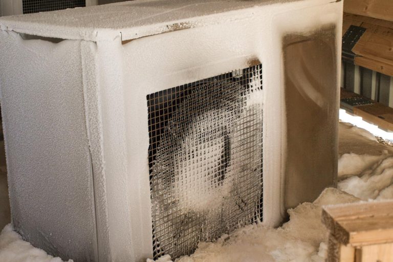 A frozen heat pump on the back of the house, How To Protect Heat Pump From Freezing Rain And Snow