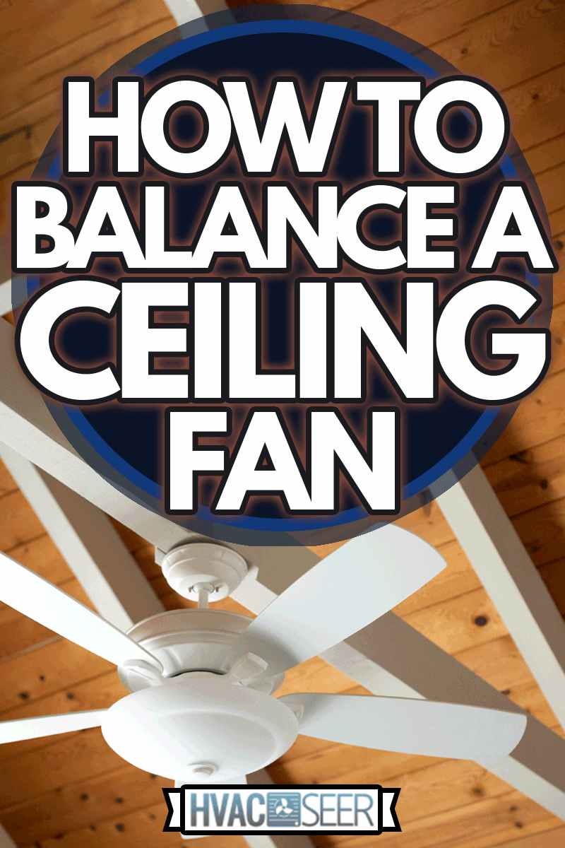 White ceiling fan on an exposed support beam, with a vaulted wood ceiling, in the living room of a modern home, with space for text on top and right side, How To Balance A Ceiling Fan