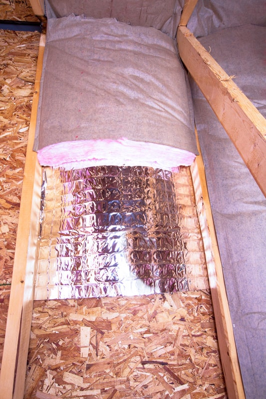 Insulation of attic with fiberglass cold barrier and reflective heat barrier between the attic joists