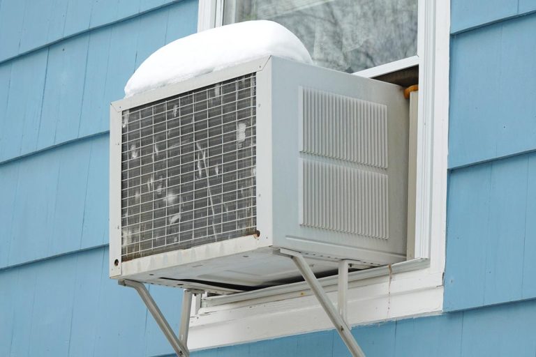 An old air conditioner installed on house window after winter snow, Can Lightning Strike A Window Air Conditioner?