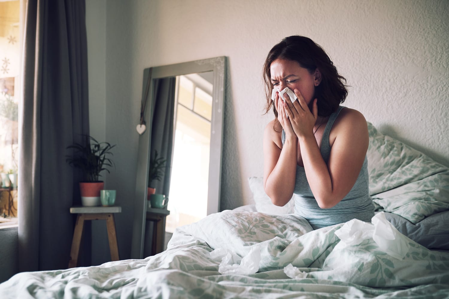 Shot of an attractive young woman suffering with the flu while sitting on her bed at home