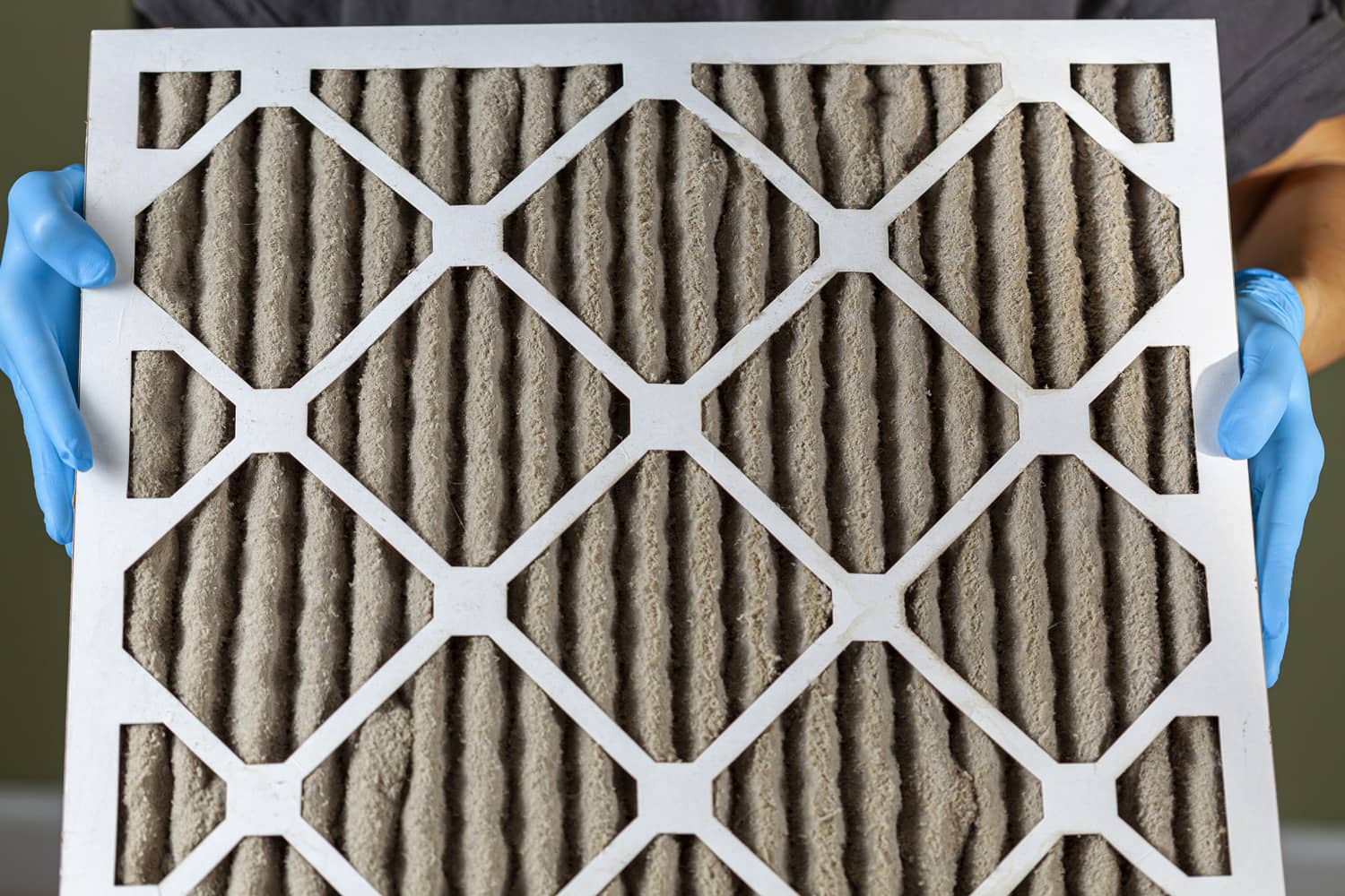 Someone holding a very dirty clogged air conditioner furnace filter