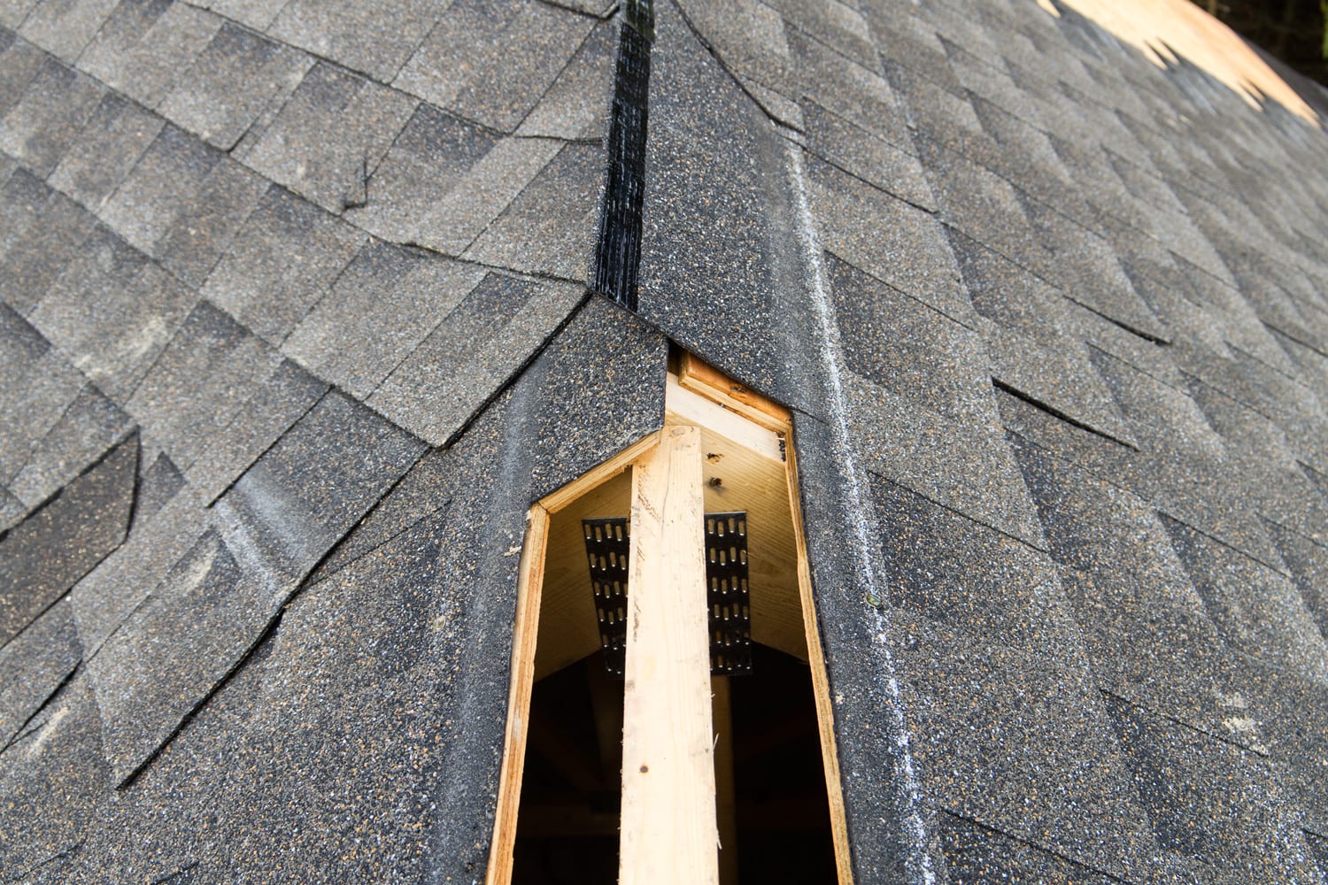 View of a partially shingled house roof, showing the cut-out for a ridge vent at the peak of the roof.Similar Images