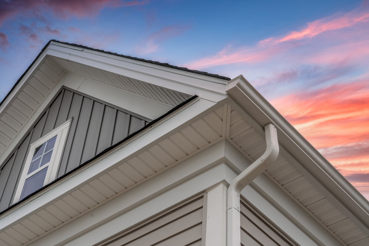 White frame gutter guard system, with gray horizontal and vertical vinyl siding fascia, drip edge, soffit, on a pitched roof attic 