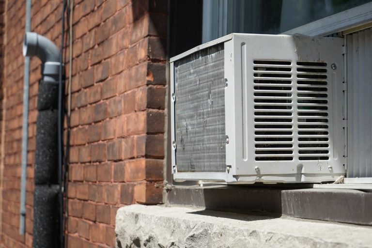 A window AC unit attached to a brick walled house, Best Air Conditioning Options For Older Homes