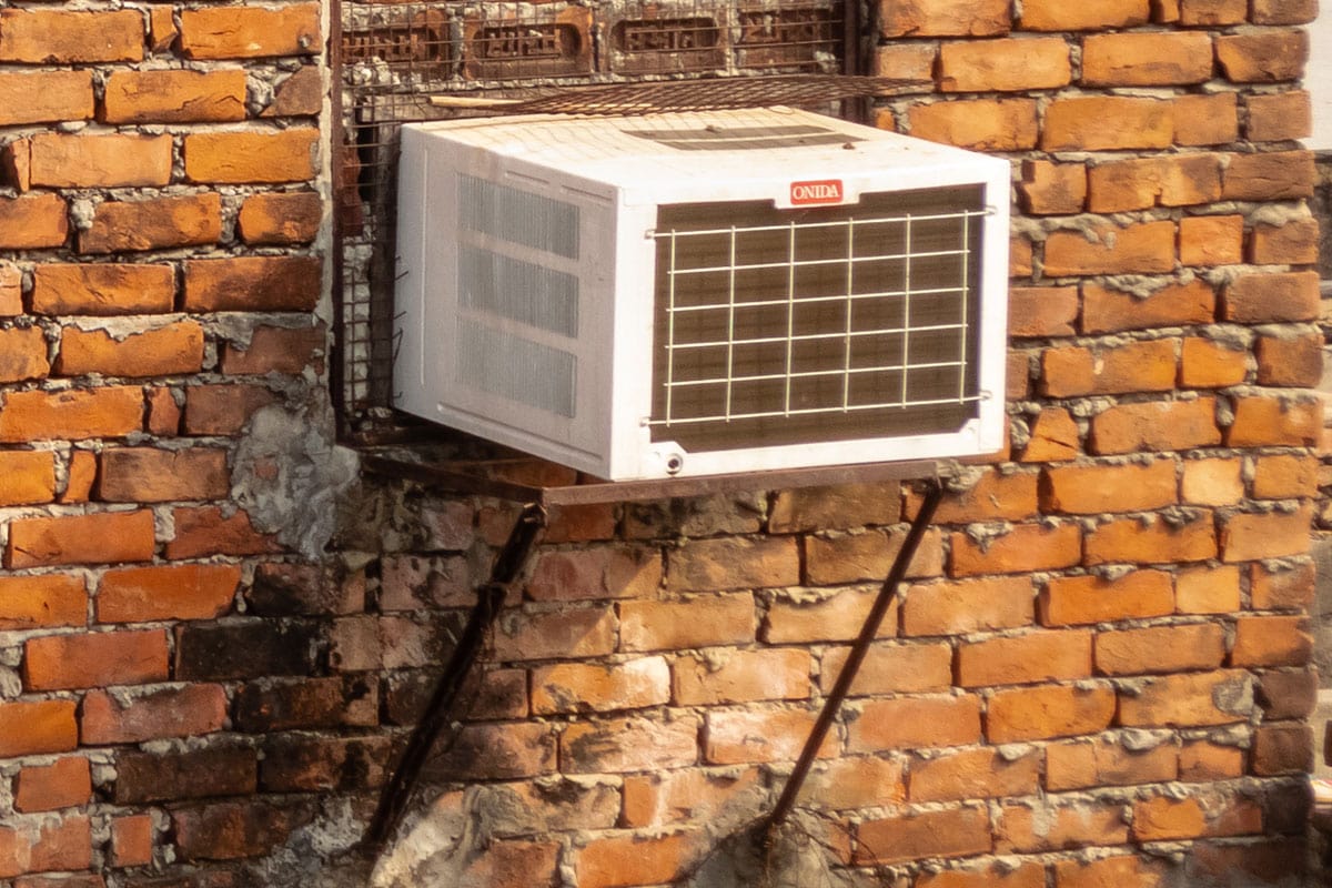 brown brick walls of a house with a mesh window and an air conditioner