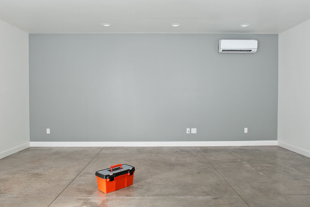floor is bare concrete and the wall has a sleek air conditioning and heating unit