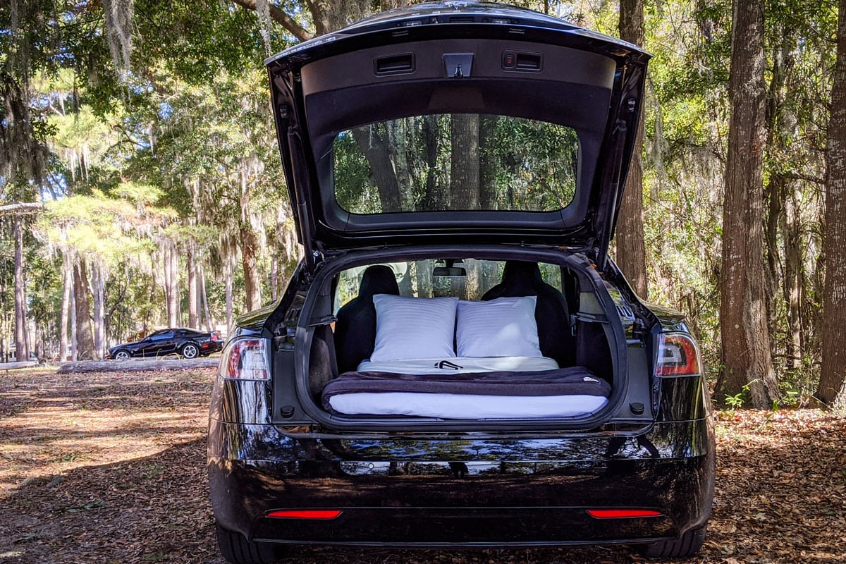 electric car equipped with a custom bed for overnight camping. Car trunk is transformed into a modern tent for luxury glamping.
