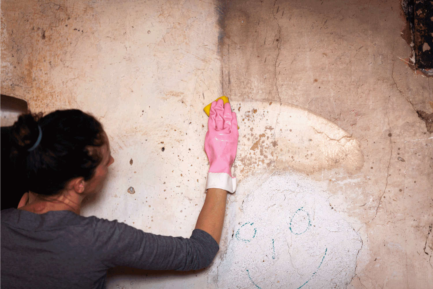 Adult Woman Cleaning Wall in an Old House using sponge
