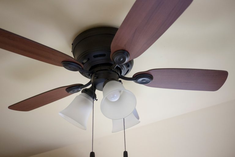 Close-up of an old ceiling fan and light fixture in a cottage in Ontario. Wooden fan blades with a black metal body and chain switches - How To Reverse A Harbor Breeze Fan
