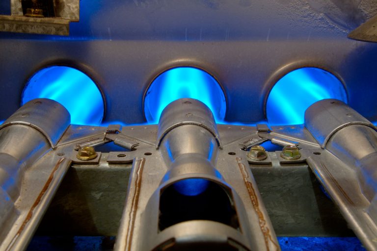 Closeup of inside a home natural gas furnace showing blue jets of fossil fuel burning, How Long Do Flame Sensors Last?