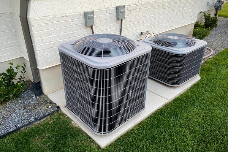Double AC units outside white brick home with green landscape and gravel, Can You Add Zones To An Existing HVAC System?