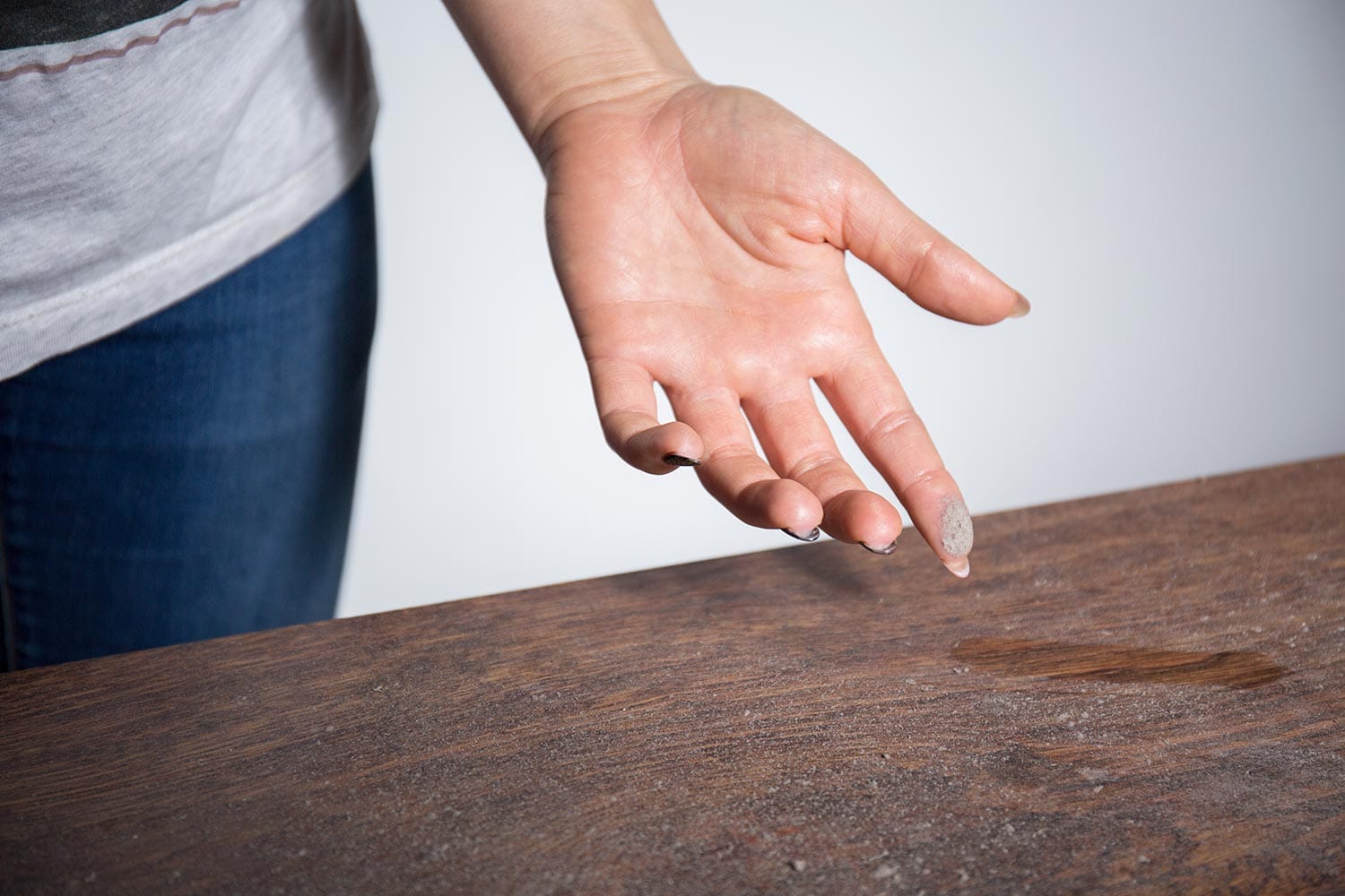 Dust on woman finger taken from wooden table