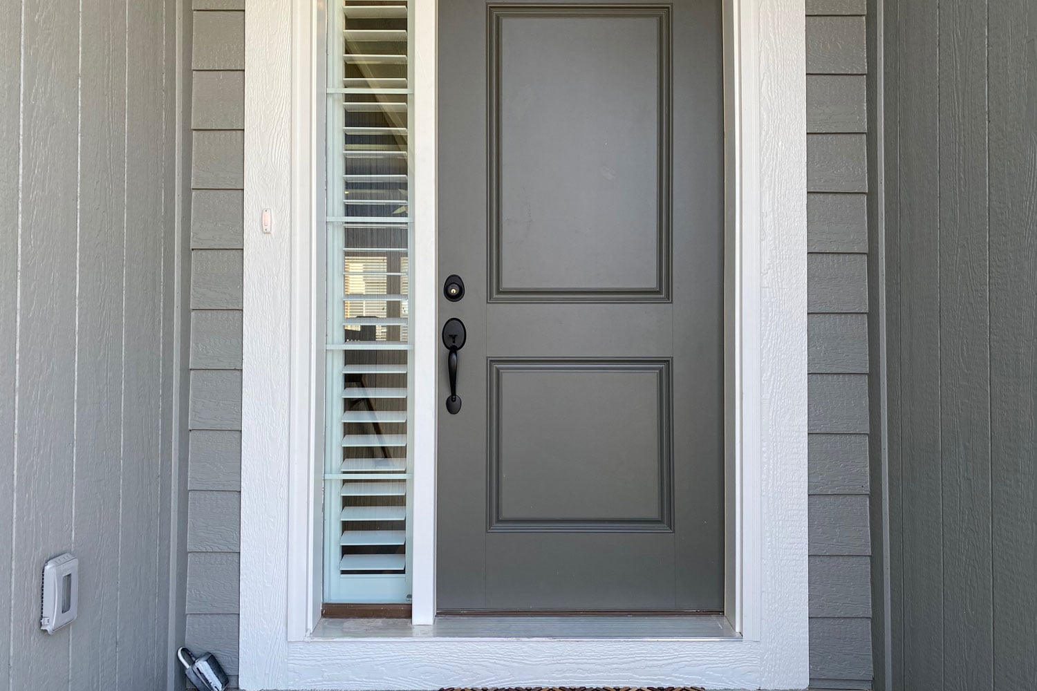 Gray front door with white trims and window panes with blinds