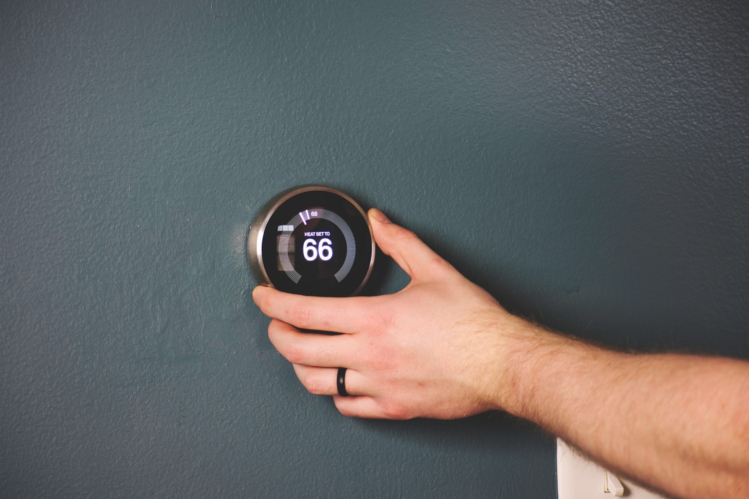 Hand adjusting temperature on electric thermostat