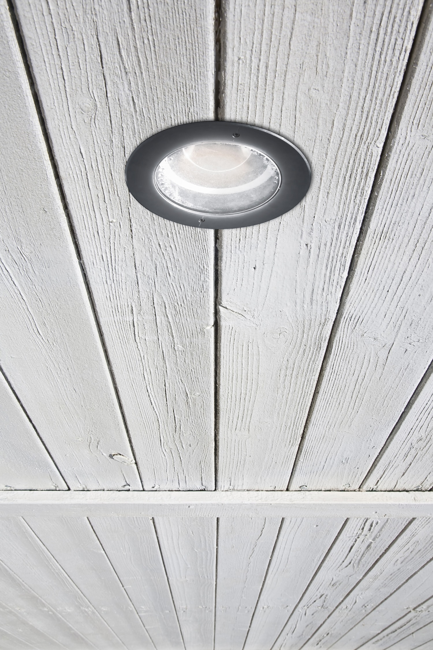 Modern metal spotlight led lamp of circular shape recessed in a wooden ceiling