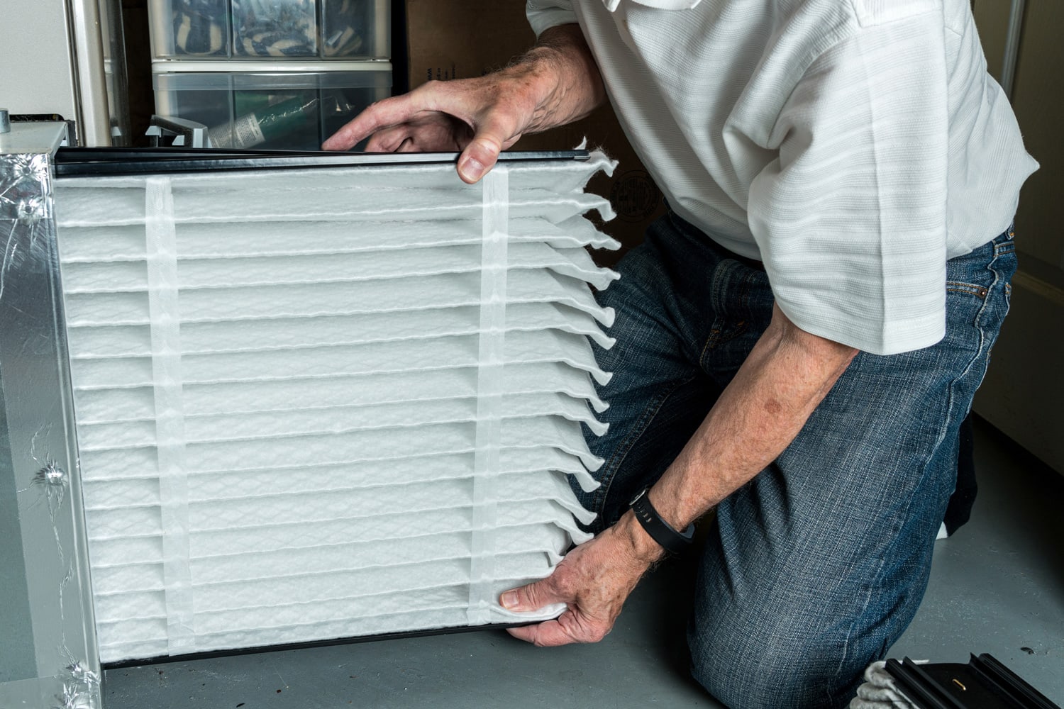 Senior caucasian man checking a clean folded air filter in the HVAC furnace system in basement of home