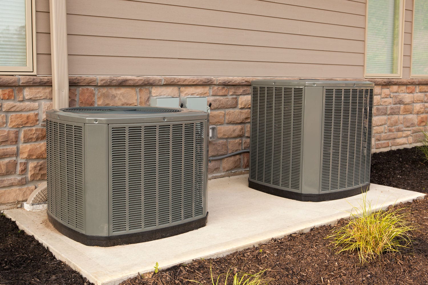 Two air conditioner units on a concrete slab