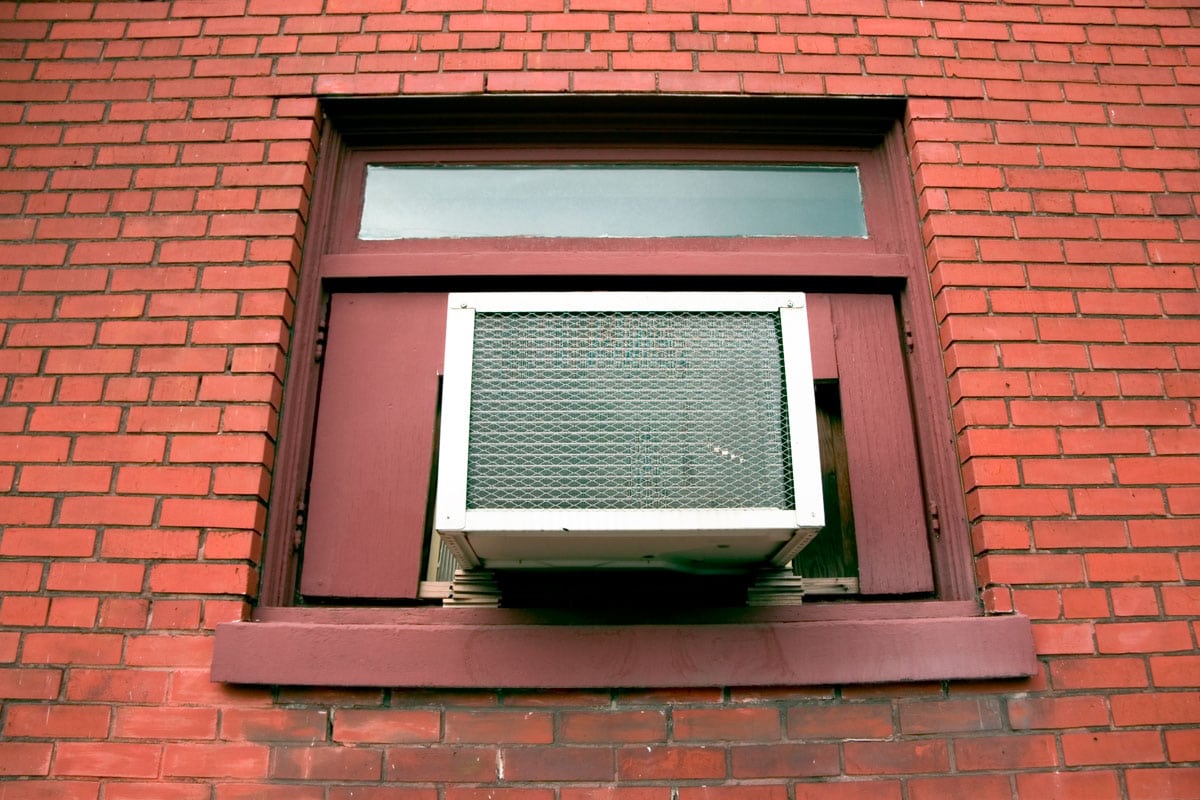 Window ac installed on a a building with concrete brick red wall