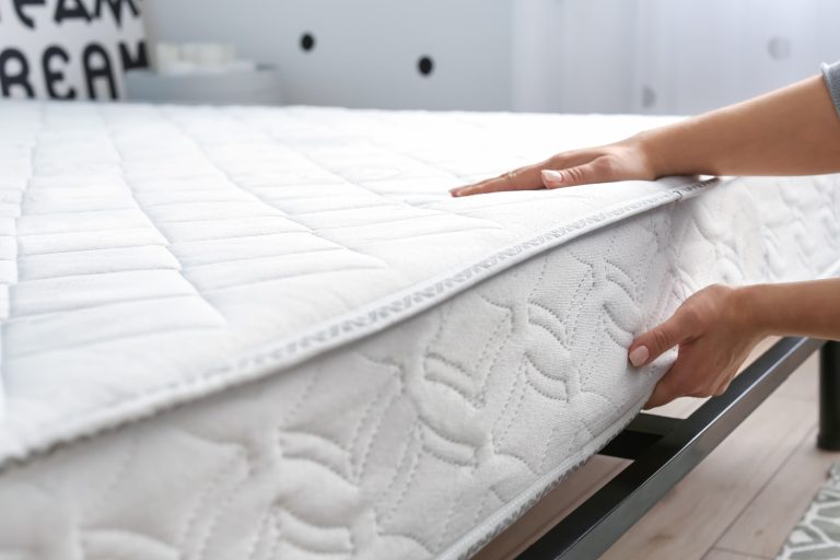 Woman putting soft orthopedic mattress on bed - How To Speed Up Mattress Off-Gassing