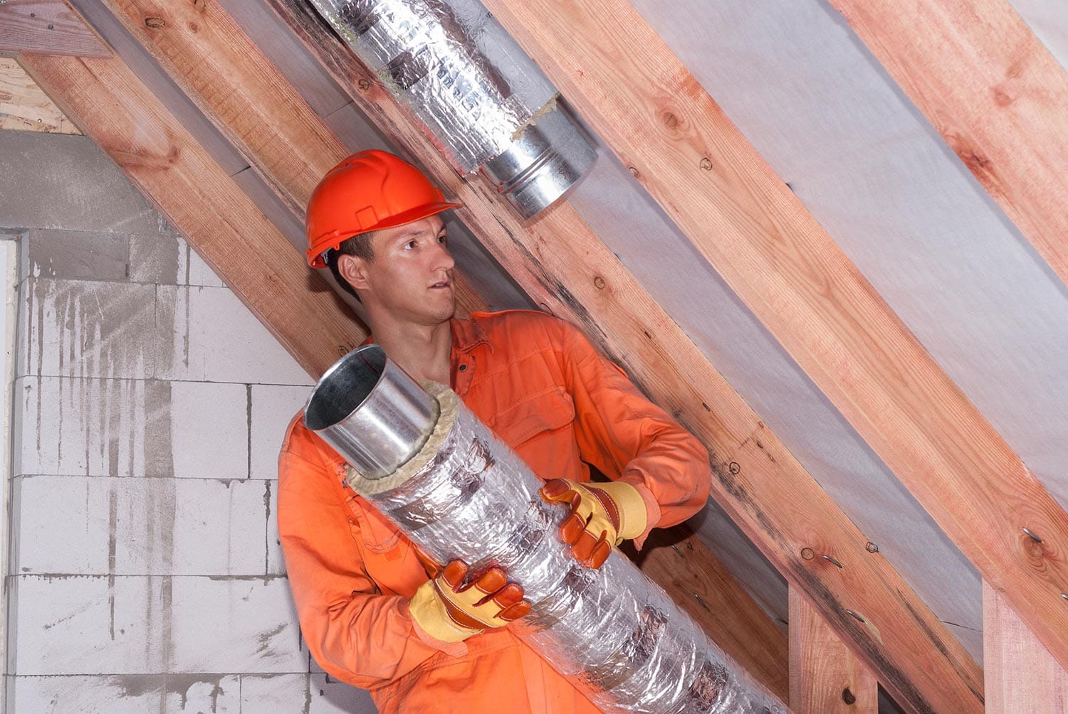 Worker in the attic connects metal air ducts