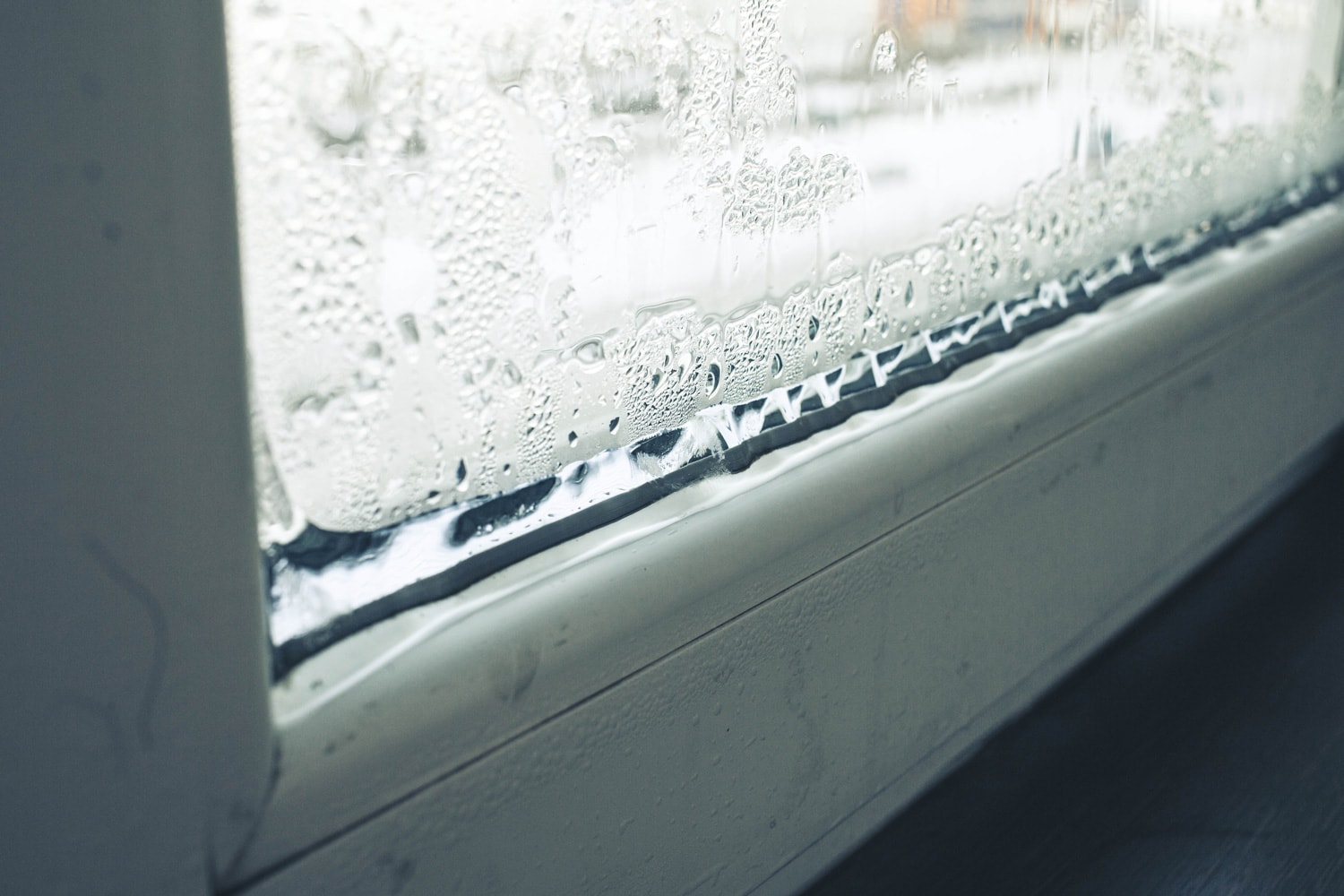 freezing of a plastic window in an apartment, frost on glass, slopes and a window sill, the foreground and background is blurred with a bokeh effect