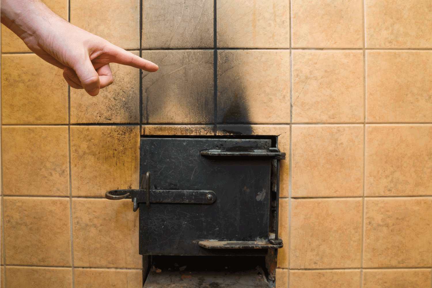 hand pointing to the soot marks from furnace on tiles wall