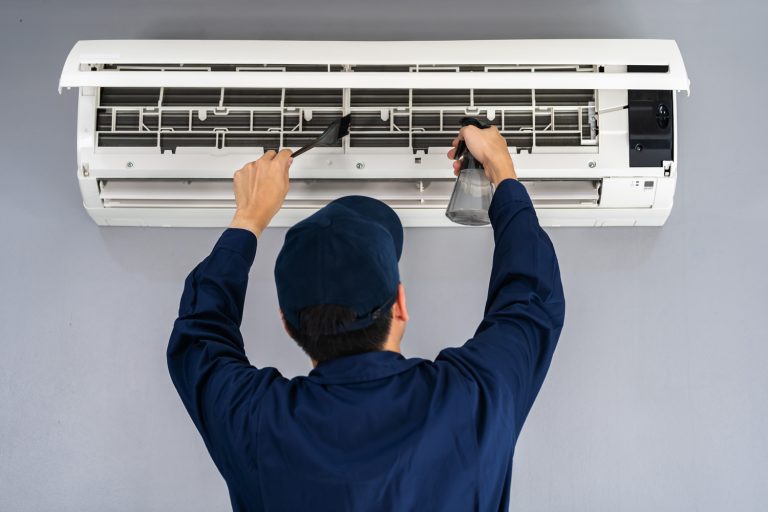 technician service cleaning the air conditioner indoors - Should AC Be Serviced Every Year