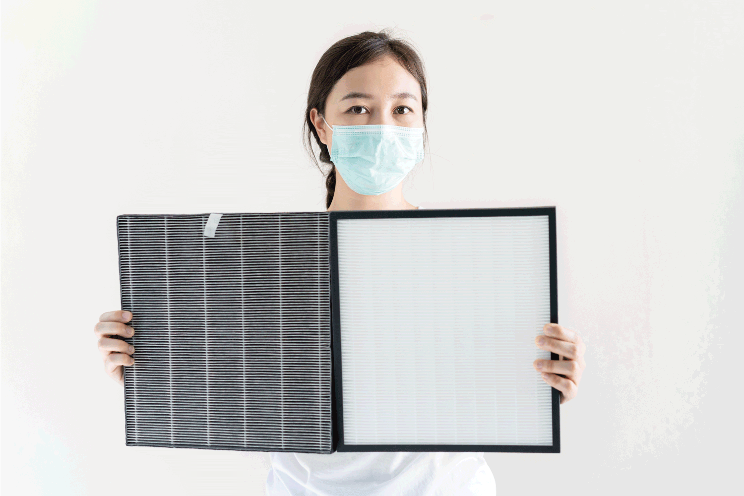 woman with protective hygiene face mask changing a HEPA air purifier filter