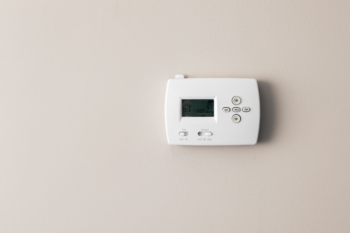 A Carrier thermostat mounted on a beige wall