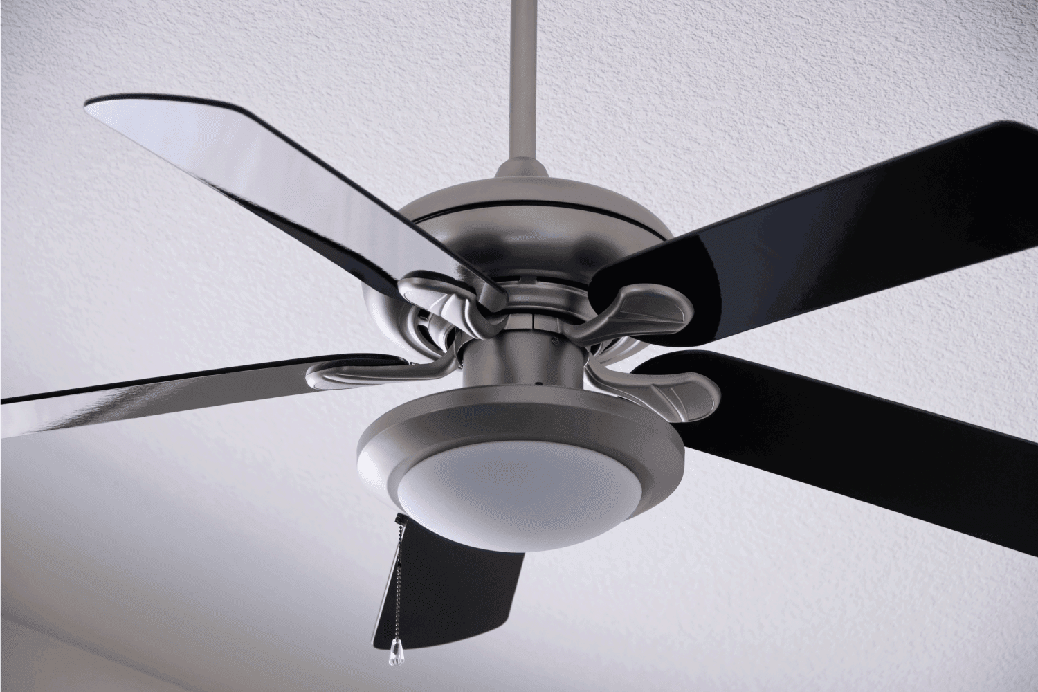 A brushed metal ceiling fan with black fins.