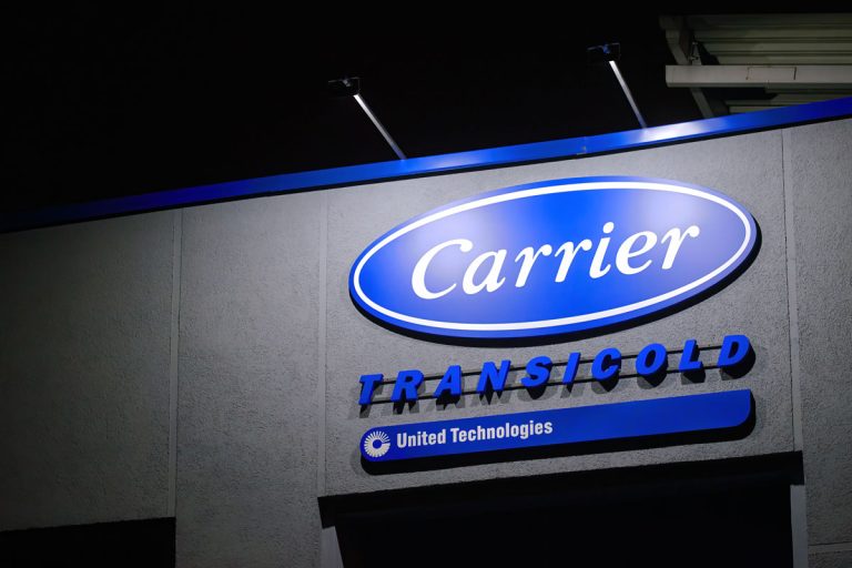 A huge Carrier logo outside a factory, How To Set Or Program A Carrier Thermostat [In 7 Easy Steps!]