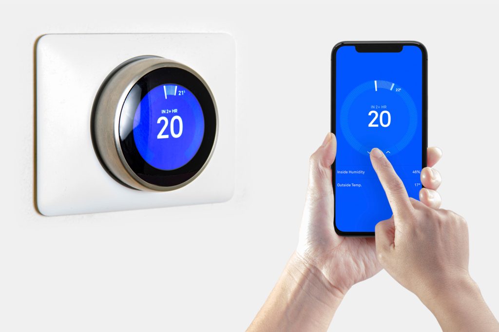 A person using a smart phone application cooling down the room temperature with a wireless smart thermostat on a white background.