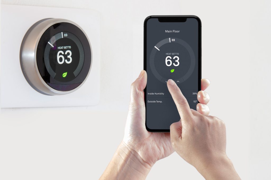 A person using a smart phone application saving energy with a wireless smart thermostat on a white background