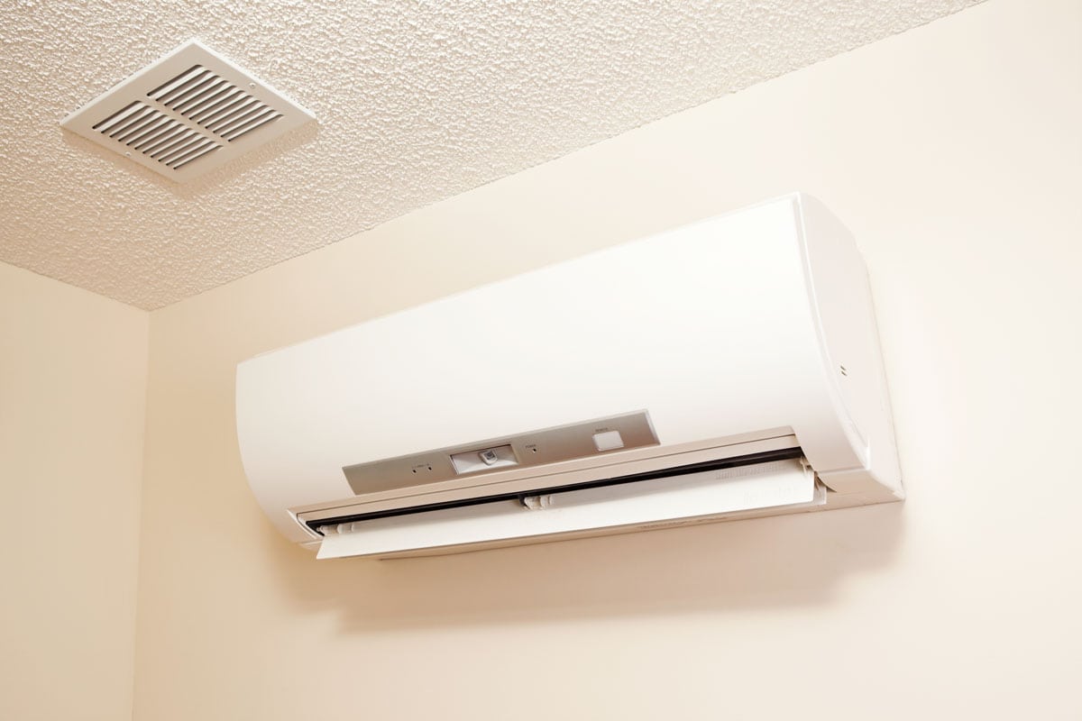 A white mini split air conditioning unit mounted on a beige wall