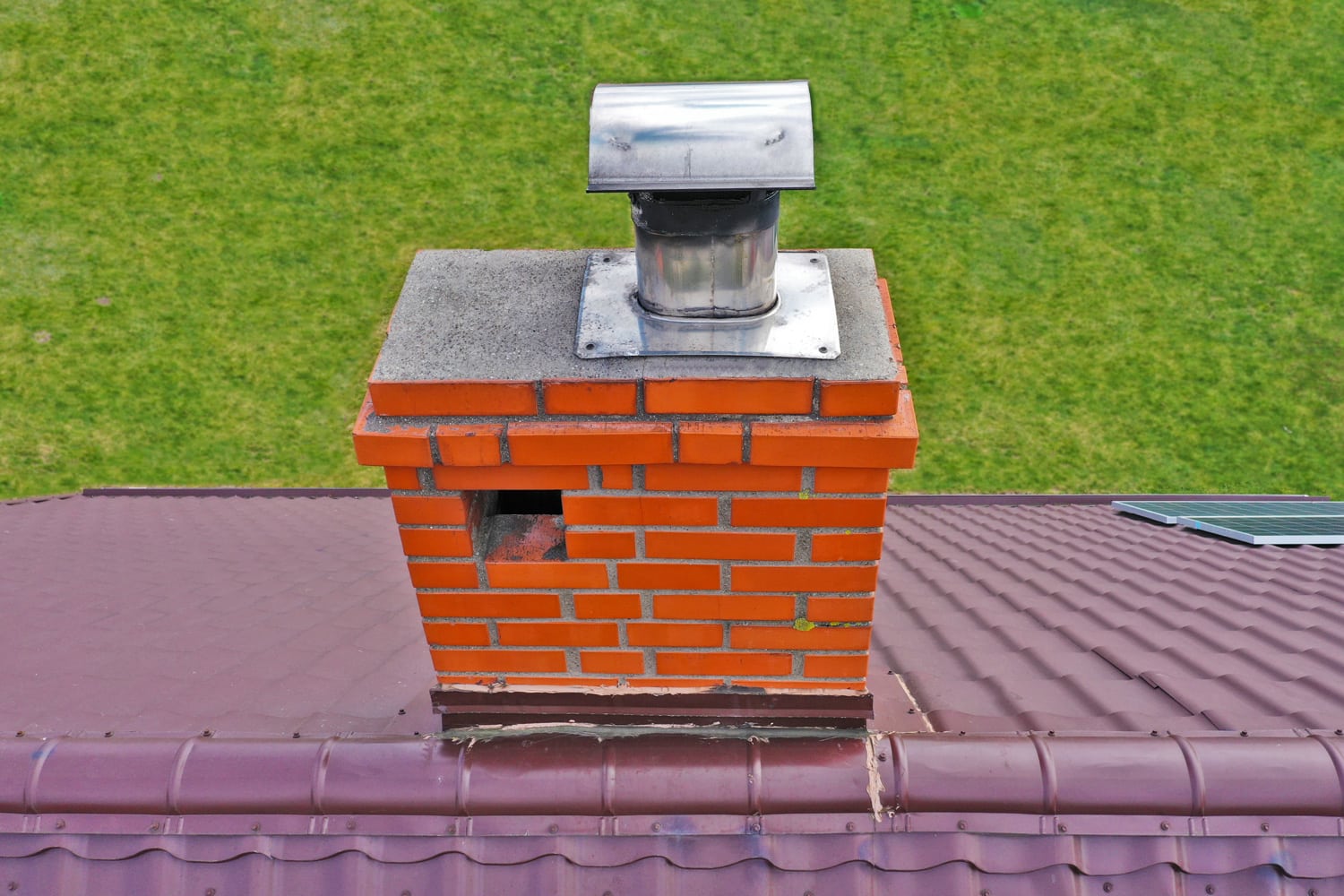 Aerial view on traditional brick chimney in red color with ventilation hole and steel pipe from furnace.
