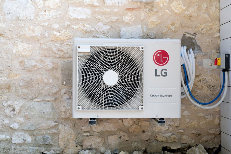 An LG smart inverter mounted on the stone wall of a house, How To Reset An LG Air Conditioner