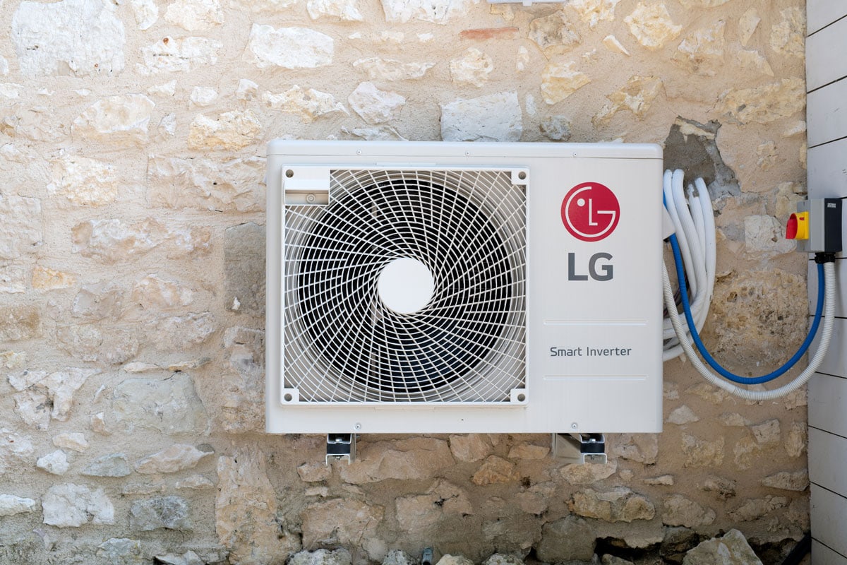 An LG smart inverter mounted on the stone wall of a house