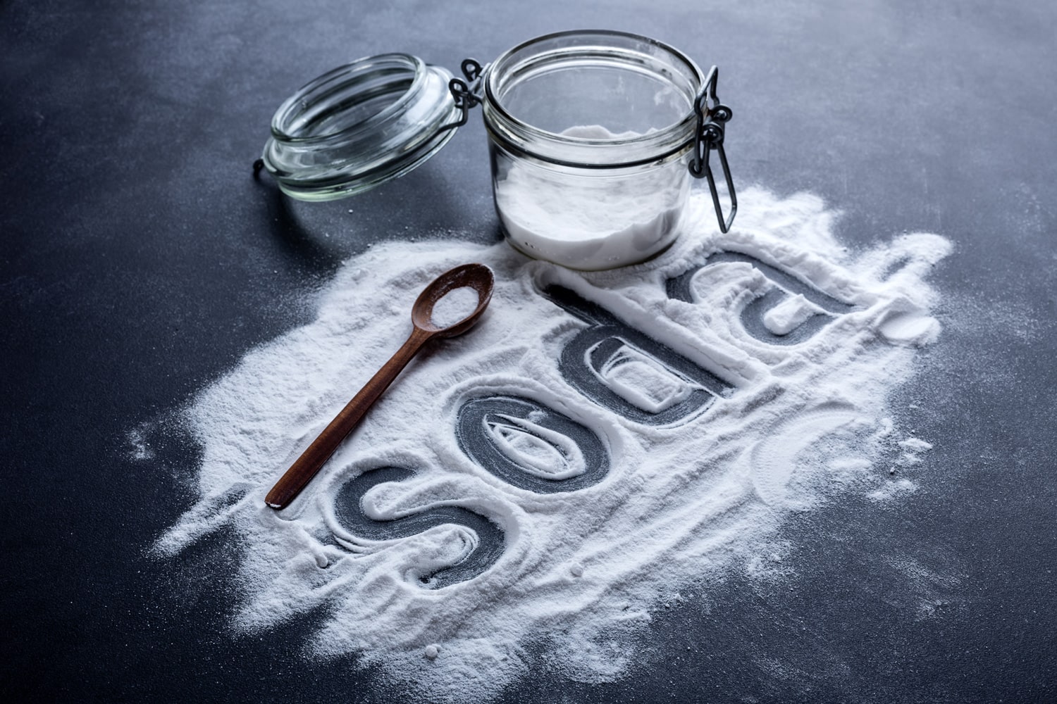 Baking soda scattered from a glass jar on a dark
