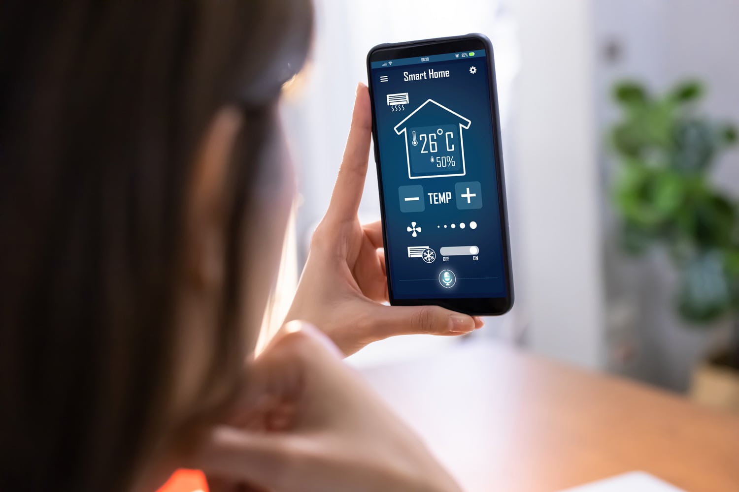 CLOSE UP of young woman using smart home app on mobile phone to control air conditioner temperature