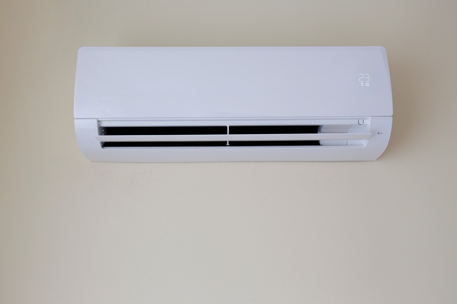 Close up shot of newly installed white air conditioner. Working AC hanging on the pastel color wall